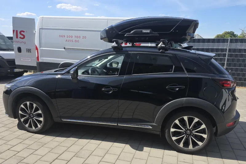 Ein Mazda CX-3 mit einer Dachbox von THULE mit 400 Liter Volumen