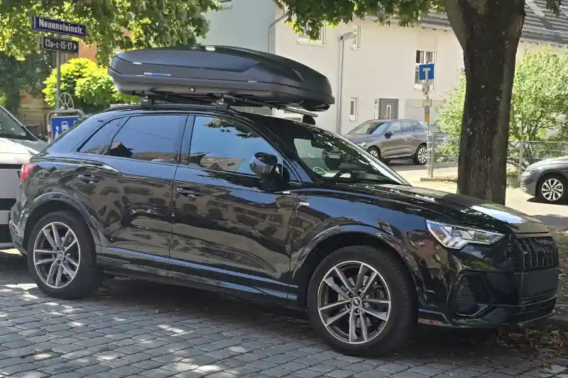 Eine Dachbox von Norauto mit Wingbar-Dachträgern von Thule auf einem Audi Q3 SUV