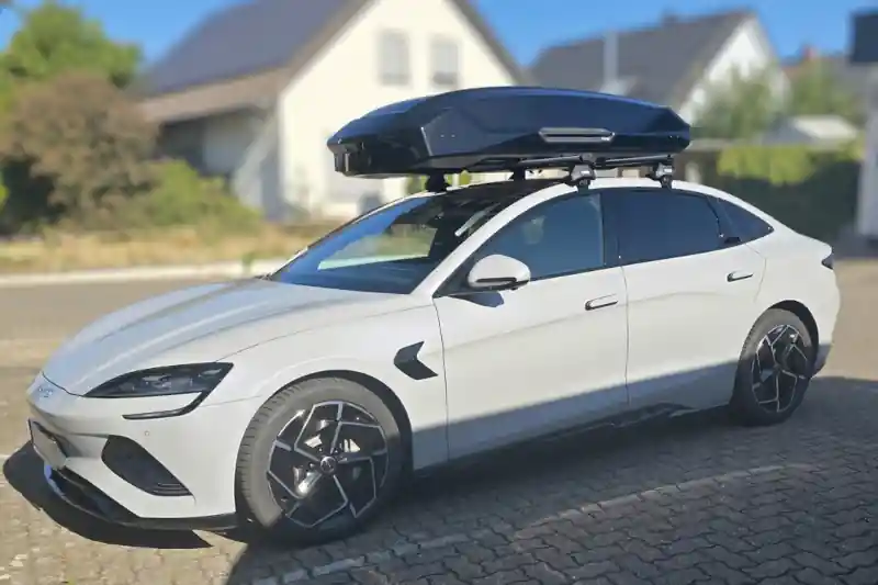 Eine Dachbox Modell Force von Thule mit Wingbar-Dachträgern auf einem BYD Seal