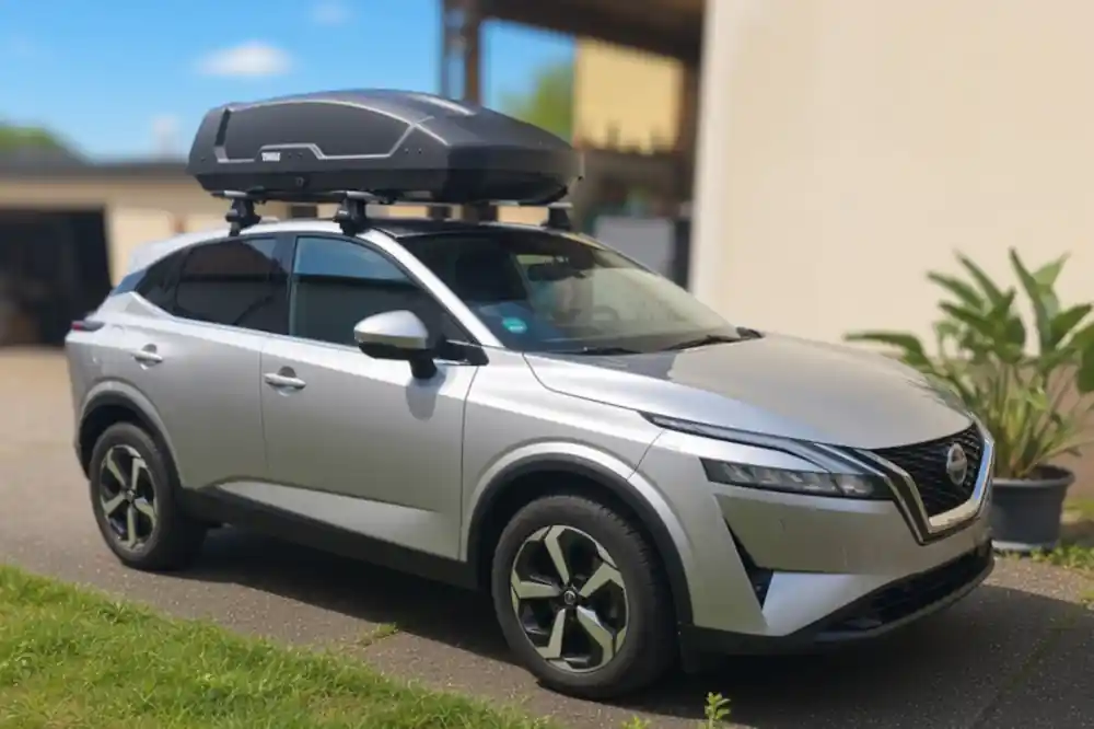 Eine Dachbox Modell Force von Thule mit Wingbar-Dachträgern auf einem Nissan Qashqai