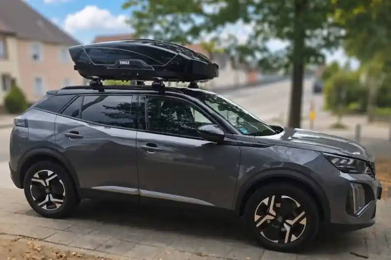 Eine Dachbox Modell Force von Thule mit Wingbar-Dachträgern auf einem Peugeot 2008
