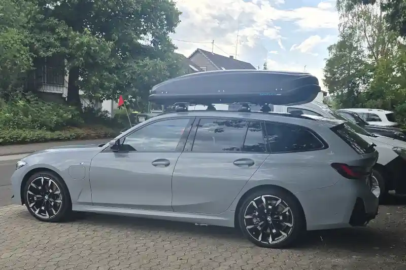 Eine Dachbox von NORAUTO mit THULE-Wingbar-Dachträgern auf einem BMW G21 Touring Kombi