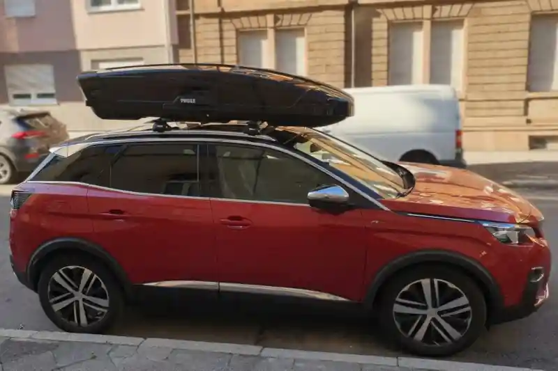 Eine Dachbox von THULE Modell "Motion XXL" mit 610 Liter Volumen mit Wingbar-Dachträgern auf einem Peugeot 3008